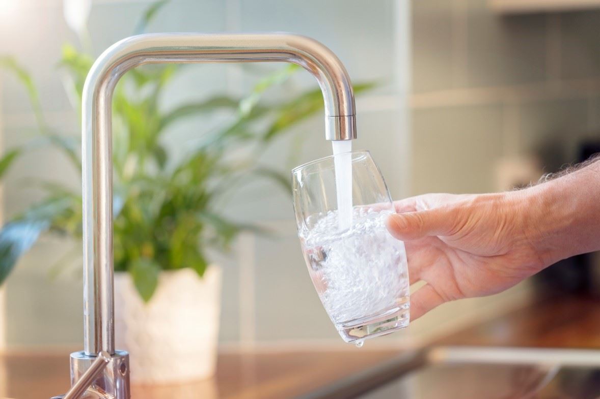 Clean water tap filling glass in household kitchen