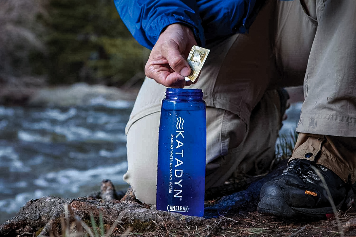 Hiker adding water purification tablet to bottle